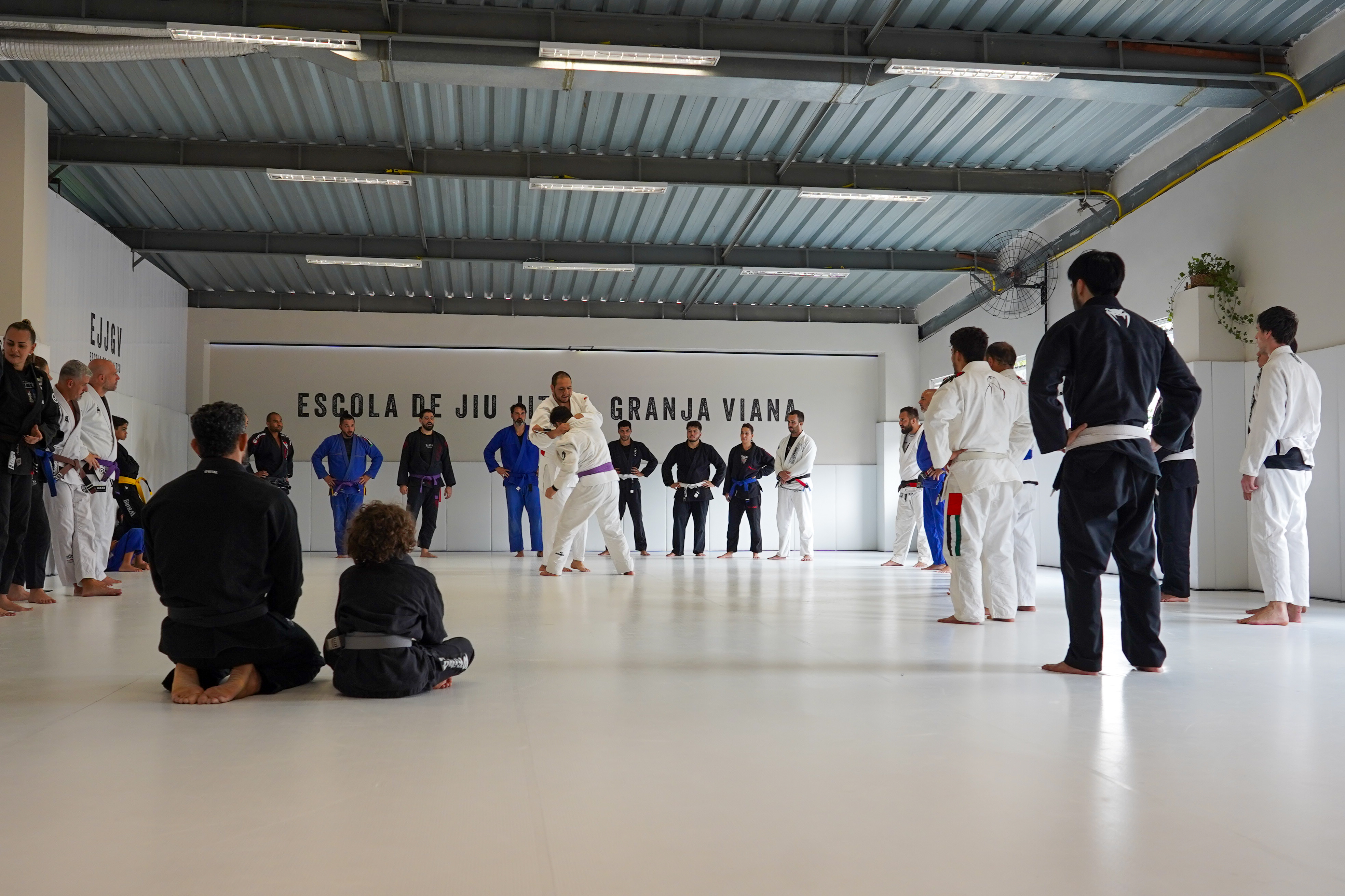 Rafael Silva demonstrando uma pegada durante clínica na Escola de Jiu-Jitsu Granja Viana, com os alunos em volta do tatame