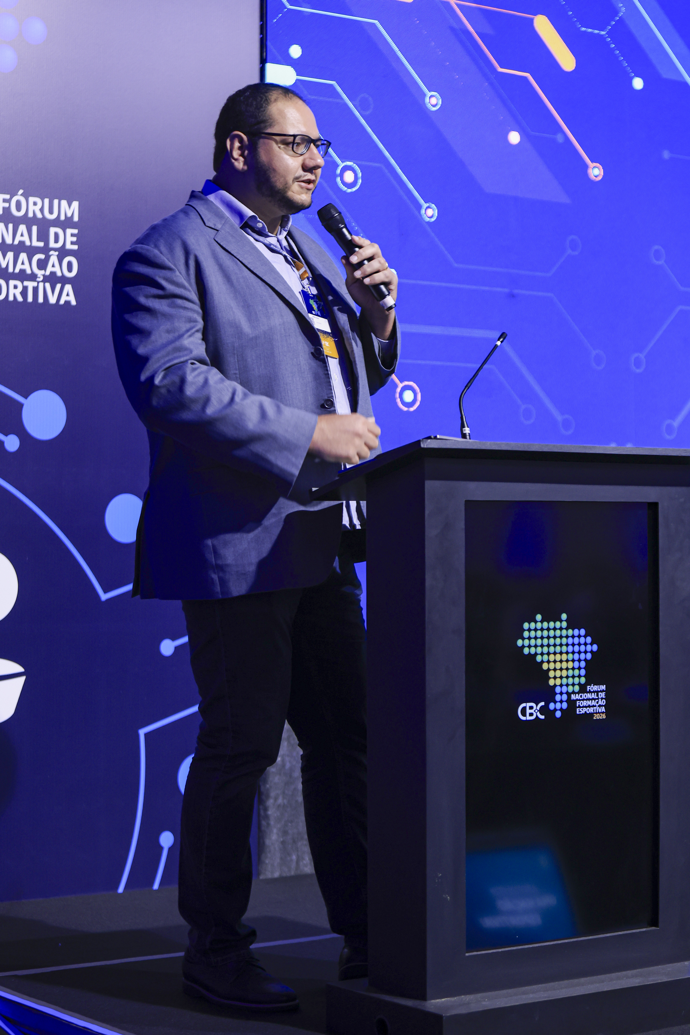 Rafael Silva de terno, microfone na mão, conduzindo o Fórum Nacional de Formação Esportiva do CBC